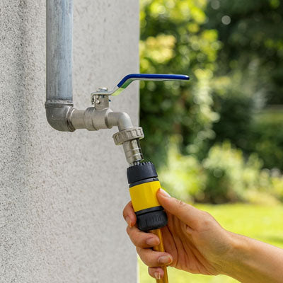 main raccorde un tuyau au robinet de jardin
